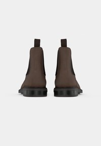 Bottes de cheville en cuir marron avec des panneaux latéraux élastiques et des languettes de tirage. Talon noir épais avec une texture striée. Fini lisse sur le cuir supérieur.