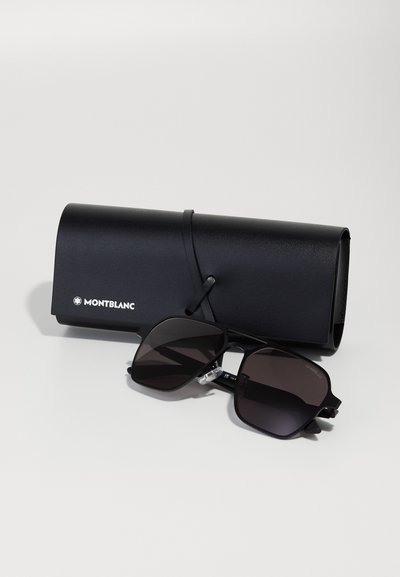 Ochelari de soare Montblanc negri cu lentile întunecate, formă octagonală și accente metalice, așezați lângă un toc rotund din piele neagră.