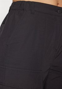 Black cargo shorts made of lightweight fabric featuring a smooth texture, elastic waistband, and two side pockets with visible stitching.