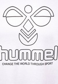 Hvid T-shirt med et logo i sort omrids, der viser abstrakte former og ordet "hummel" med sætningen "FORANDR VERDEN GENNEM SPORT" nedenfor.