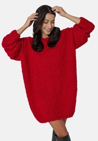 Przesadnie duży czerwony sweter z puszystego materiału o teksturowanym wykończeniu. Opuszczone ramiona i ściągacz u dołu. Luźny, przewiewny krój.