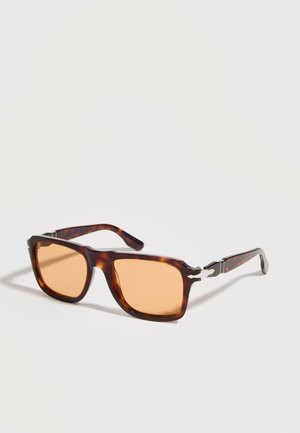 Pravokotna sončna očala v vzorcu želvje lupine z lečami jantarne barve in srebrnimi kovinskimi poudarki na stranicah, prikazana na belem ozadju.