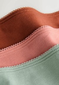Échantillons de tissu tricoté en trois couches en rouille, rose poussiéreux et vert sauge avec des bords de couture festonnés.