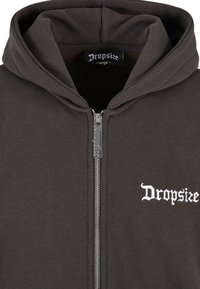 Gray zip-up hoodie made of cotton blend fabric, featuring a large hood and white embroidered brand name on the left chest.