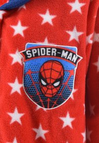 Red fleece fabric with white star patterns, featuring a Spider-Man patch in blue, black, and red, outlined in white stitching.