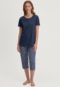 Navyblauwe katoenen T-shirt met een ronde hals, gecombineerd met navy en witte cropped broeken met stippen. Eenvoudig en casual ontwerp.