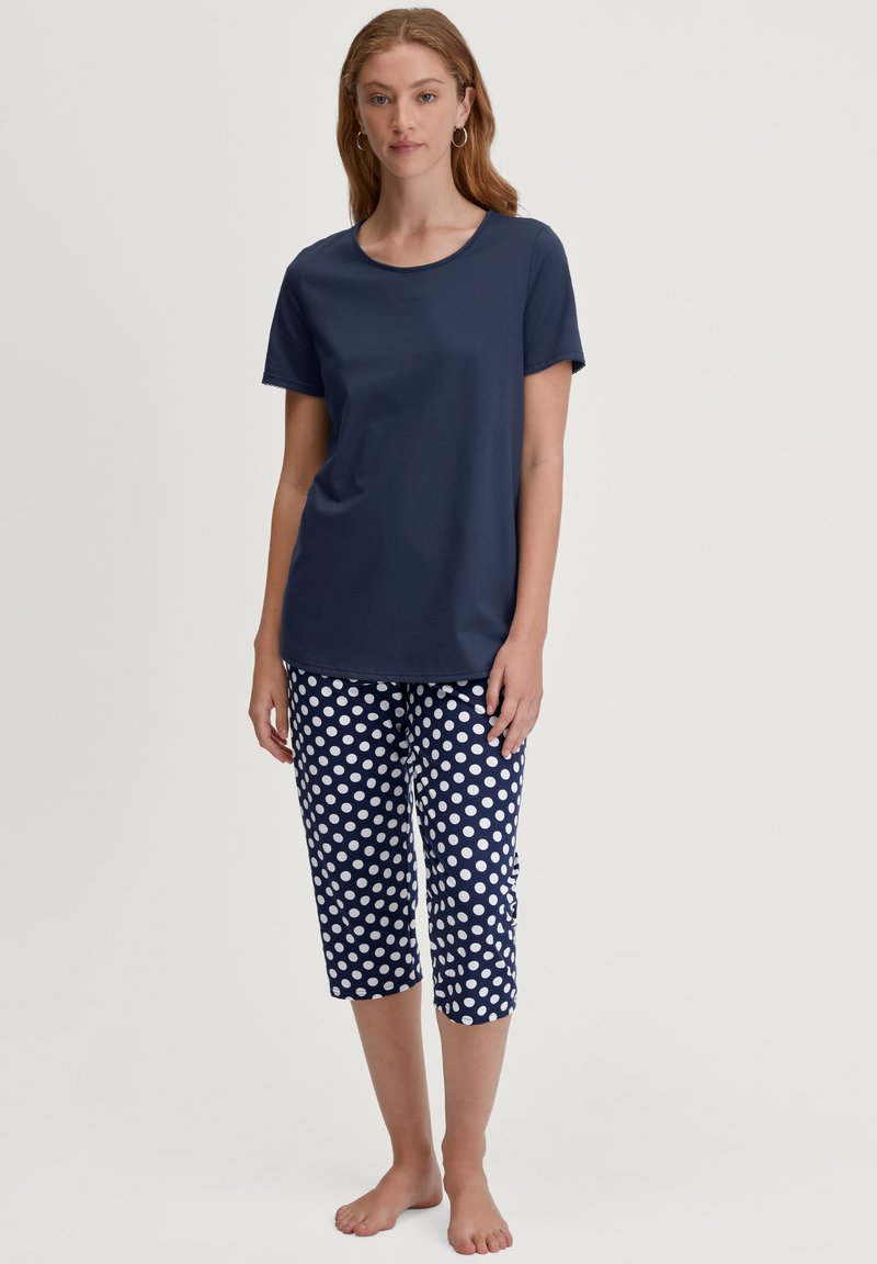 Navyblauwe katoenen T-shirt met een ronde hals, gecombineerd met navy en witte cropped broeken met stippen. Eenvoudig en casual ontwerp.