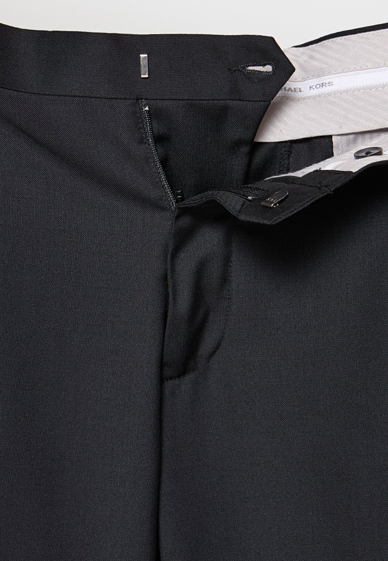Zwarte broek met open ritssluiting, haak-en-oogsluiting en zichtbare witte binnenbandvoering gelabeld met Michael Kors.