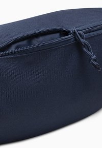 Custodia con zip di colore blu navy realizzata in tessuto texture, caratterizzata da una zip resistente e una forma arrotondata. Adatta per riporre piccoli oggetti.