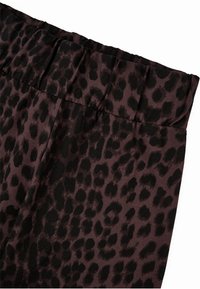 Leopardenmusterstoff in verschiedenen Schattierungen von Dunkelbraun und Schwarz, mit einem strukturierten Bund und glatter Oberfläche, die für Elastizität ausgelegt ist.