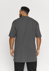 Grau kurzärmliges T-Shirt aus Baumwolle mit lockerer Passform. Es hat einen Rundhalsausschnitt und einen leicht abgerundeten Saum hinten.