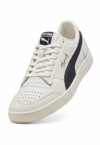 Hvide lædersneakers med sorte accenter, perforeret tå, tekstureret gummisål og signaturdetalje på siden. Klassisk snøredesign.