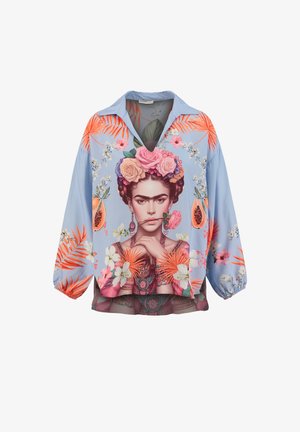 Blouse bleu clair avec imprimé floral coloré et fruits de papaye, présentant un portrait détaillé d'une femme avec des fleurs dans les cheveux et une rose dans la bouche.