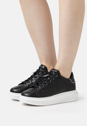 Sneakers neri a basso con un design testurizzato, tomaia in pelle liscia, suola in gomma bianca e lacci neri. Accentuati da dettagli con logo.