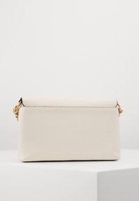 Pochette en cuir couleur crème avec une finition texturée, quincaillerie dorée et une forme rectangulaire structurée. Design élégant et minimaliste.