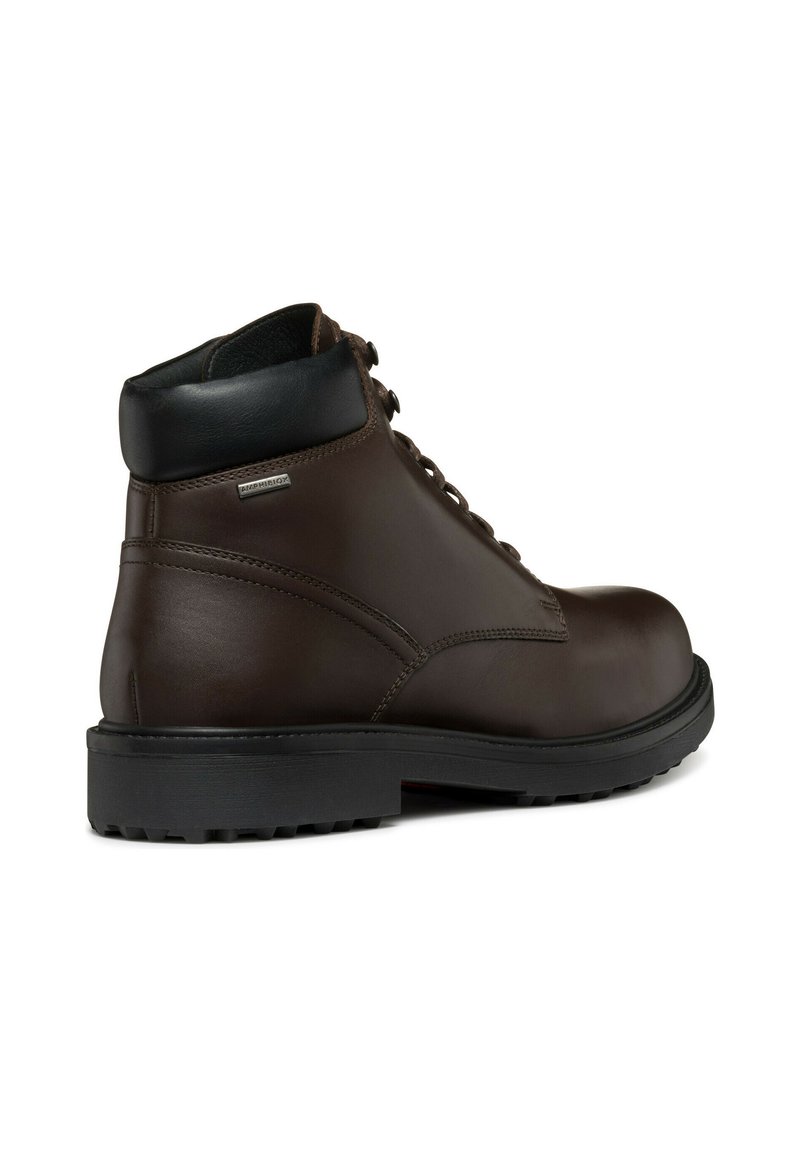 Bota de cuero marrón hasta el tobillo con cuello acolchado negro, suela de goma negra gruesa y etiqueta metálica "Amphibiox" en el lado exterior.