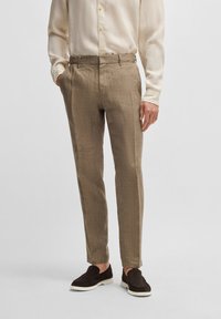 Ljusbeige linnebyxor med texturerad yta, smal passform, framfickor och bälteshällor. Kvalitetssko i mörk färg och en krämfärgad skjorta.