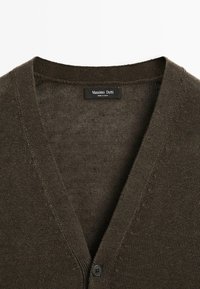 Brown knitted cardigan with a V-neck design, featuring a single button closure and a textured, soft fabric. Brand label visible inside.