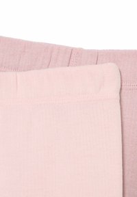 Secciones de tela de algodón en rosa claro y malva con textura acanalada. Detalles de costura visibles a lo largo de los bordes, lo que indica un diseño de ajuste relajado.