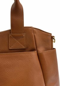 Sac à main en cuir marron avec une finition texturée, doté de poches latérales robustes, de poignées plates et d'accents en métal doré.