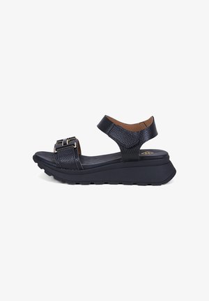 Sandale à plateforme en cuir noir avec brides réglables à la cheville et à l'avant, dotées de boucles métalliques et d'une semelle épaisse en caoutchouc.