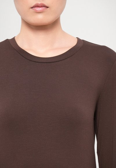 Ruskea pitkähihaisen paita, joka on valmistettu sileästä kankaasta ja jossa on pyöreä kaula-aukko. Yksinkertainen ja vartaloa myötäilevä muotoilu, ei näkyviä kuvioita tai koristeita.