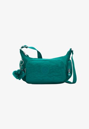 Türkisfarbene Umhängetasche aus strukturiertem Stoff, mit einer Fronttasche, einem runden Logo-Patch und einem Affen-Schlüsselanhänger.