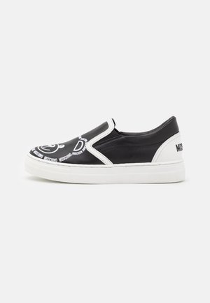 Sort og hvid slip-on sneaker med hvid sål, tegneserieansigt og teksten "Moschino" trykt på tåen og hælen.
