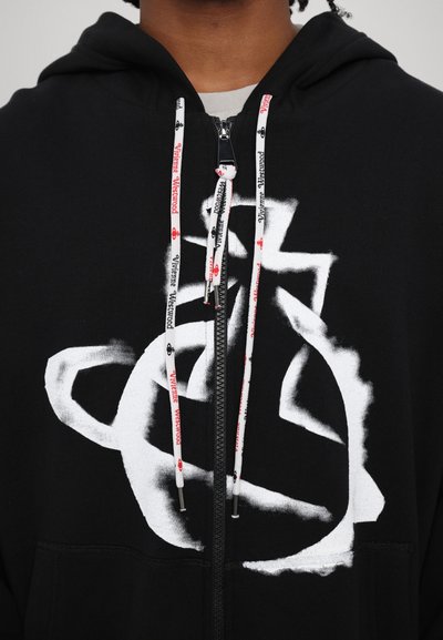 Black hoodie with white graphic design; features zip closure, drawstrings with red and white branding, and a soft fabric texture.