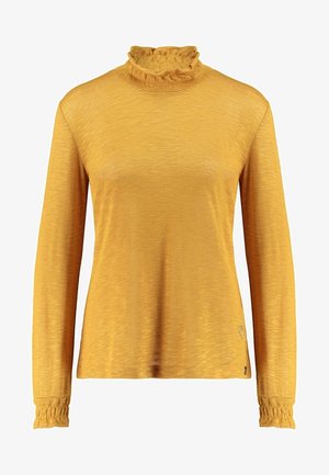 Haut pour femmes à manches longues couleur jaune moutarde avec col montant et poignets à volants, en tissu doux et texturé.