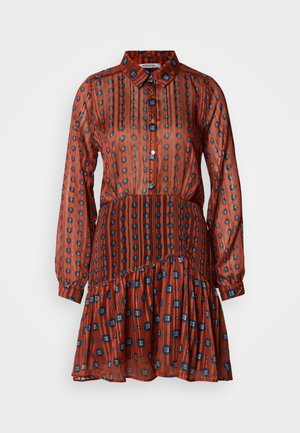 Rochie roșie din material transparent, cu mâneci lungi, guler tip cămașă, închidere cu nasturi și tiv cu volane în straturi. Are dungi verticale cu modele geometrice albastre și negre.