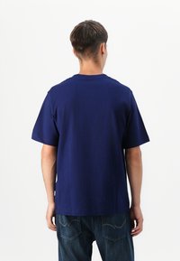 Mørkeblå bomulds t-shirt med korte ærmer, rund hals og en afslappet pasform, der har en lige kant og et minimalistisk design.
