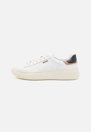 Baskets basses blanches avec semelle crème, détail talon noir et marron, fermeture à lacets, et logo "BOSS" sur le côté.