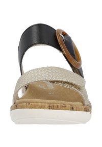 Sandali con una fascia in finta pelle nera, una banda intrecciata beige e una fibbia decorativa circolare marrone. Presentano una soletta in sughero e una suola bianca.