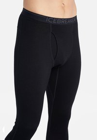 Pantaloni termici neri con un design aderente, realizzati in un tessuto liscio, dotati di un elastico in vita a media altezza contrassegnato "ICEBREAKER" e una patta funzionale.