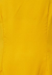 Tissu jaune vif avec une texture douce et une finition lisse. Présente des coutures subtiles le long des coutures, créant une forme structurée.