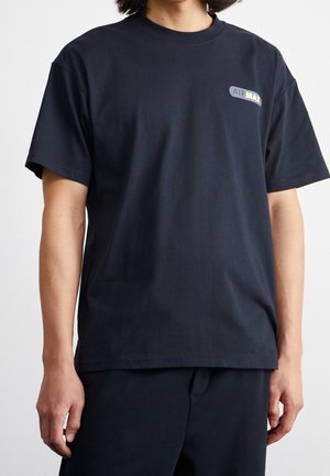 Zwarte katoenen t-shirt met een ronde hals, korte mouwen en een klein logo label met de tekst "AIR MAX" in geel en grijs op de linkerkant van de borst.