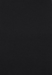 Tissu noir côtelé avec une surface texturée. Les rayures verticales sont uniformes sur toute la surface. Le matériau semble extensible et moulant.