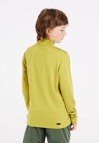 Lange mouwen coltrui in fel limoen groen, gemaakt van een gladde stof. Heeft een relaxte pasvorm en een klein logotag aan de onderrand.