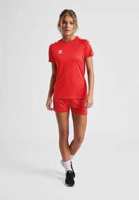 Röd fukttransporterande träningsset bestående av en kortärmad topp och shorts, med kontrasterande vita detaljer. Mjuk, lättviktig tyg.