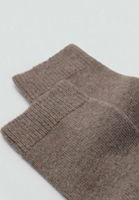 Calzini marroni in misto cotone con polsini a coste e una texture liscia, piegati ordinatamente per mostrare entrambi i lati e le cuciture.