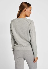 Light grey sweatshirt with a crew neckline, ribbed cuffs, and hem. Made from soft, textured fabric with raglan sleeves.