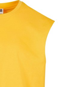 Gul ærmeløs T-shirt lavet af bomuld. Har en rund halsudskæring og blød tekstur. Enkel design uden synlige mønstre eller dekorationer.