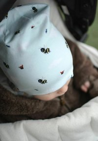 Vaaleansininen puuvillapipo, jossa on mustia ja keltaisia mehiläisiä, leppäkerttuja sekä pieniä hyönteisiä kuvioina. Pehmeä rakenne ja tiukka istuvuus.