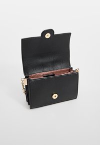 Portafoglio in pelle nera texturizzata con chiusura a scatto dorata, dotato di un compartimento aperto, scomparti interni per carte e tracolla a catena rimovibile.