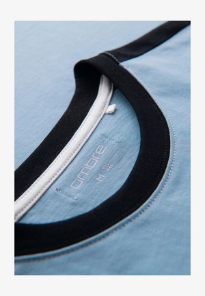 Lichtblauw T-shirt met een zwarte geribbelde kraag en witte details, met een label waarop het merk en de maat aan de binnenkant zijn gestikt.