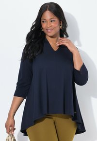 Navy blue, V-kaula toppi, jossa on kolme neljännestä hihoista, roikkuva muoto, pehmeä kangas, yhdistettynä sinapinkeltaisiin housuihin, joissa on kultasävyinen yksityiskohta.