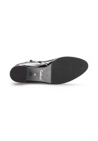 Zapato de charol negro con suela de goma plana, punta cuadrada y un diseño mínimo en los detalles. Presenta un sutil patrón texturizado en la suela.