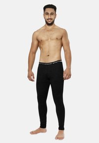 Schwarze Sportleggings aus elastischem Material mit einem markierten Bund. Der Schnitt liegt eng am Körper an, ohne auffällige Muster.