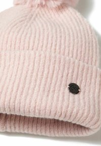 Cappello lavorato a maglia di un delicato rosa chiaro con una texture a coste, dotato di un soffice pom-pom sulla sommità e di un piccolo etichetta scura cucita nel tessuto.